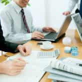 Colleagues sitting around desk surrounding business technology