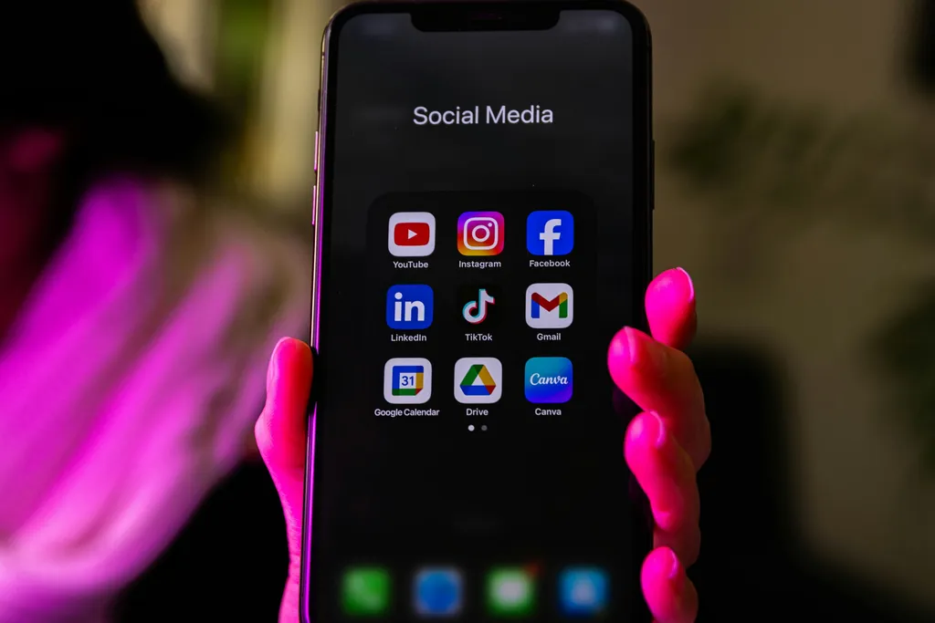 Hand holding a smartphone showing social media apps including TikTok