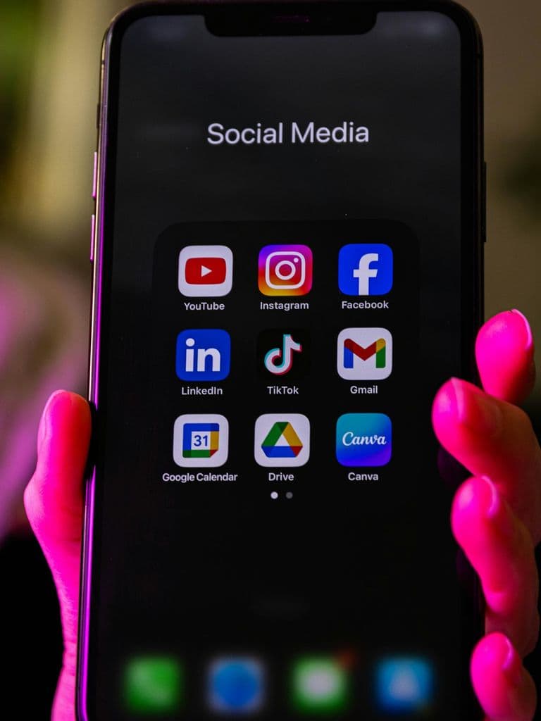 Hand holding a smartphone showing social media apps including TikTok