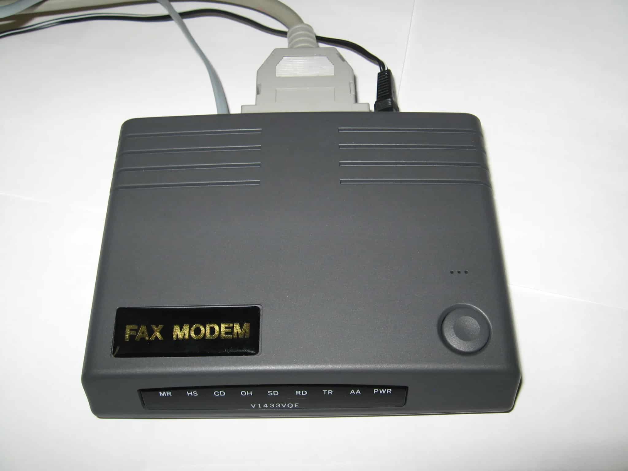 A gray external dial-up fax modem with cables attached, photographed on a plain white background.