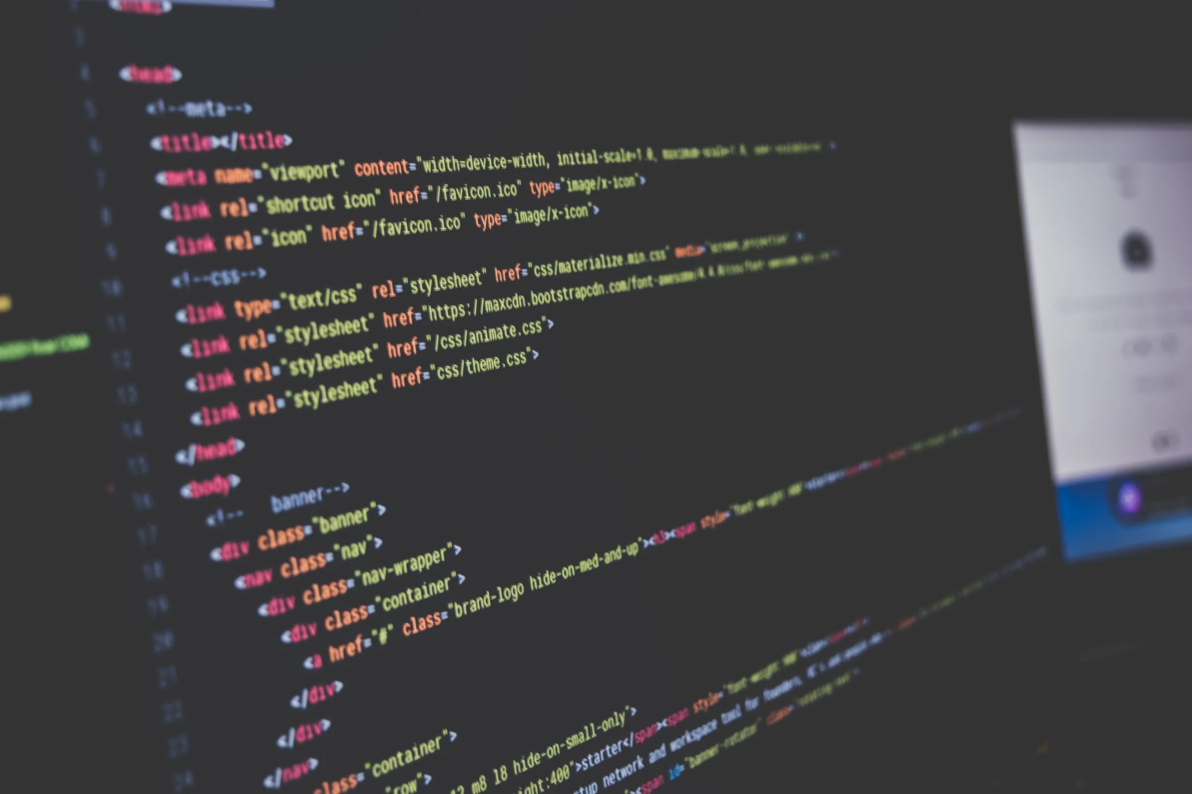 Close-up of a computer monitor displaying lines of colorful code in a dimly lit room.