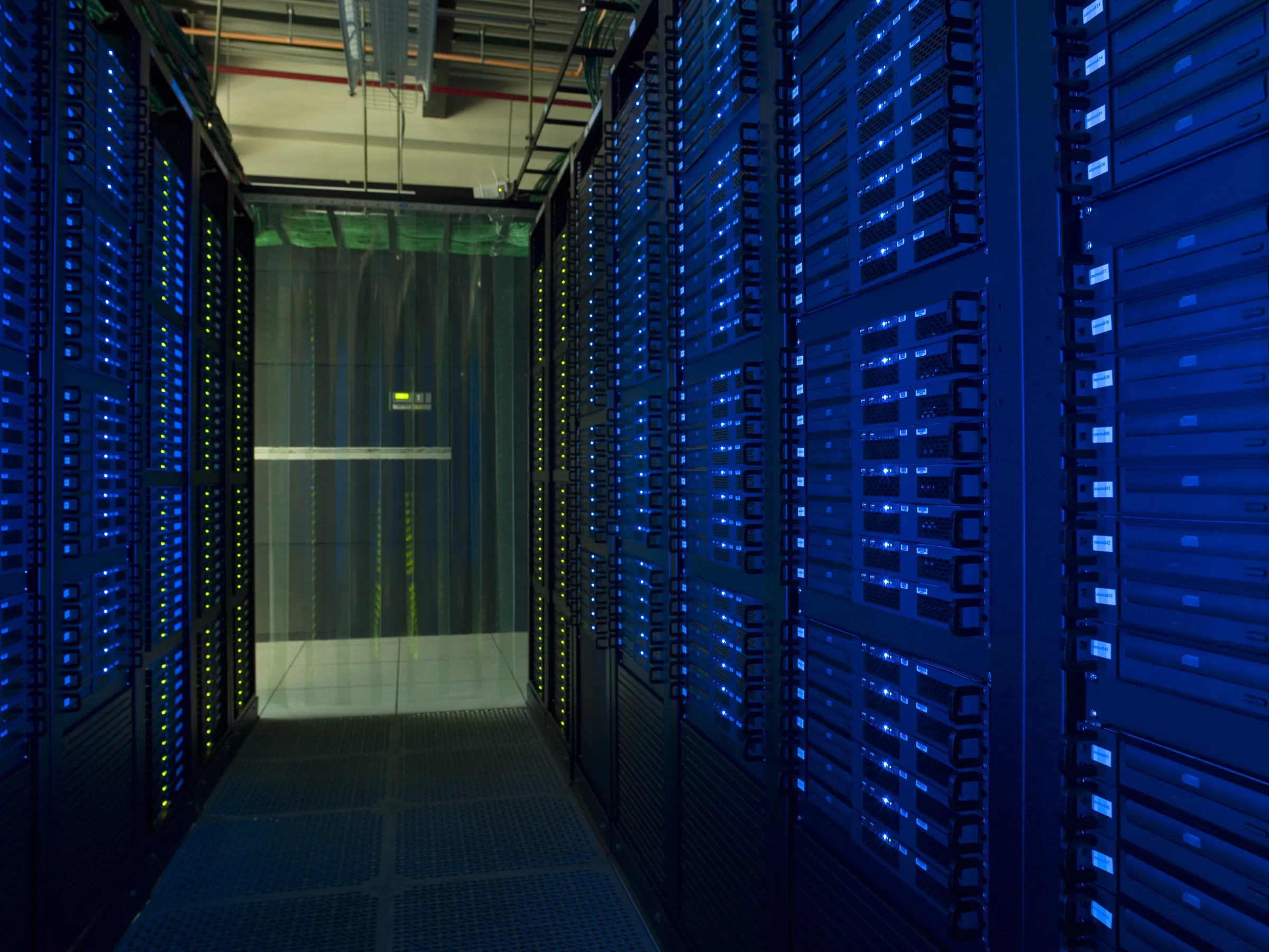 A long row of server racks glowing with blue and green status lights in a dimly lit data center corridor.