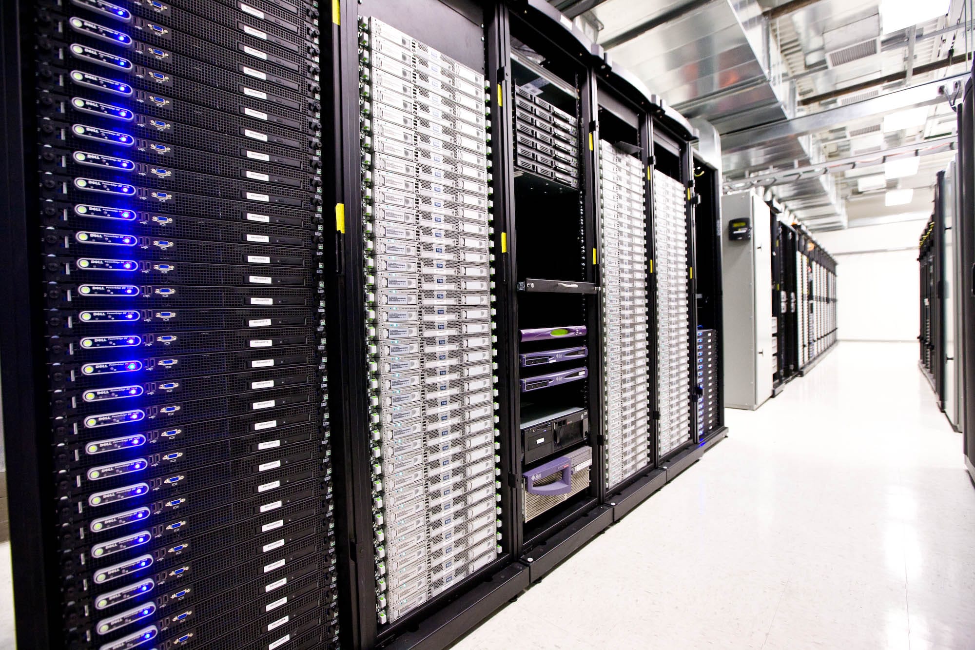 A row of server racks with glowing blue and white status lights lining a data center aisle.