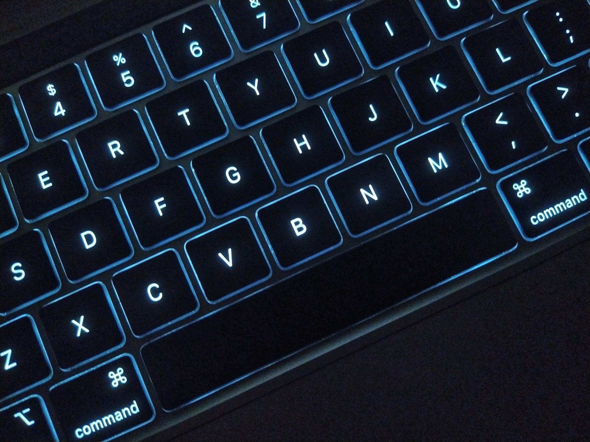 A close-up of a backlit MacBook keyboard highlighting the command key.