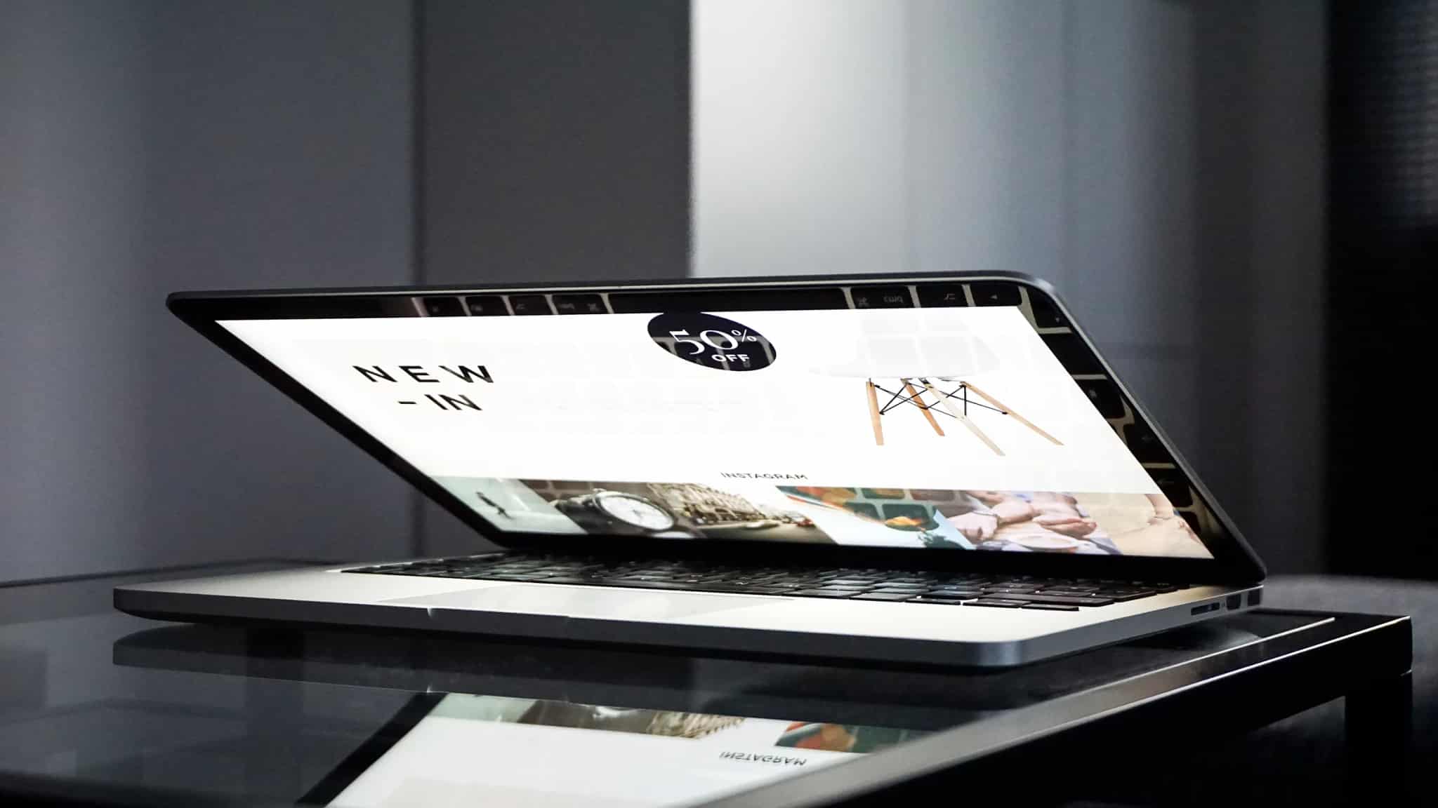 A low-angle view of a laptop screen displaying an online store's homepage with a '50% off' promotion and product photos.