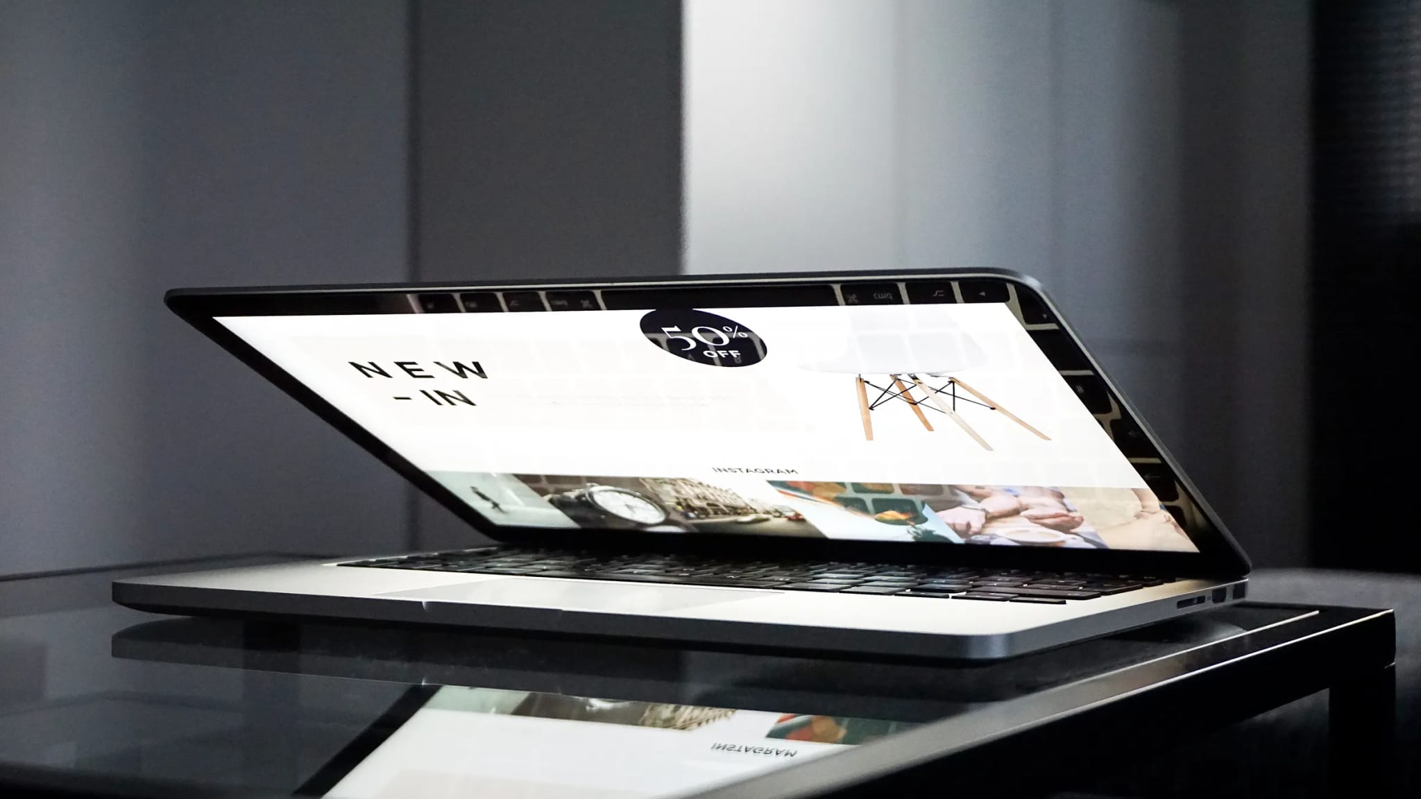 A low-angle view of a laptop screen displaying an online store's homepage with a '50% off' promotion and product photos.