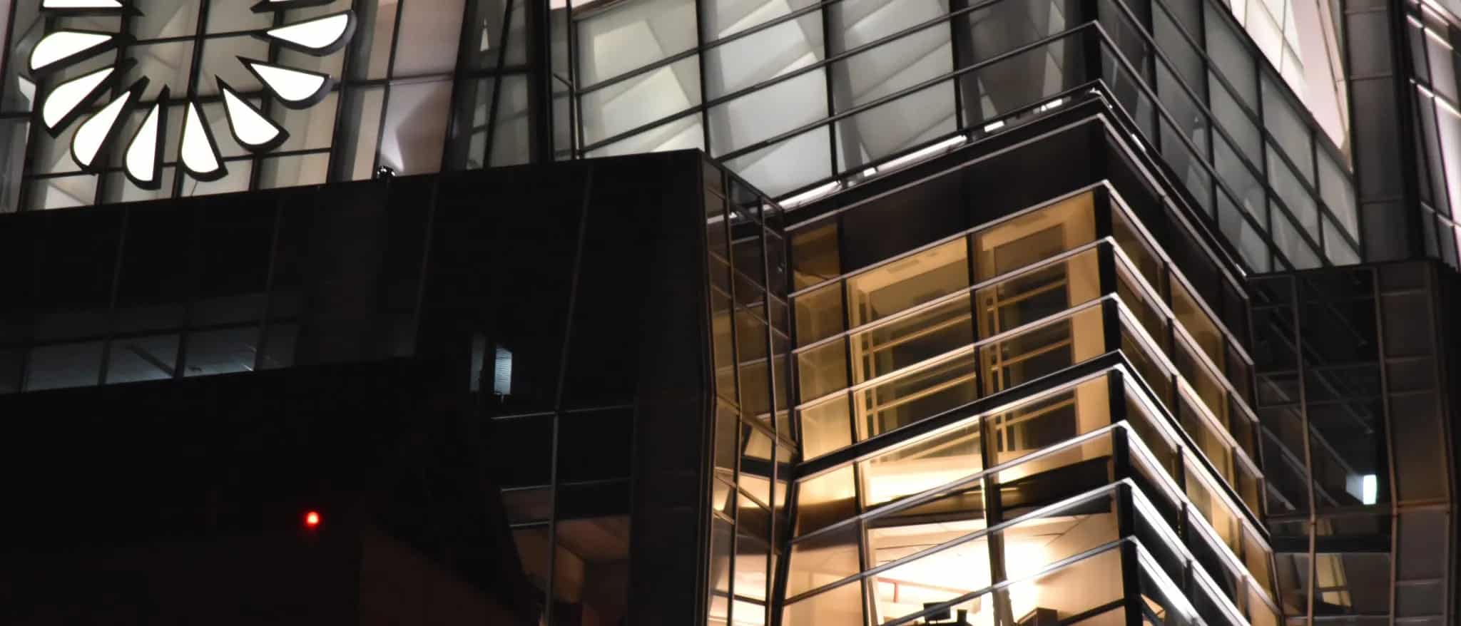 A modern glass office building lit up from within at night.