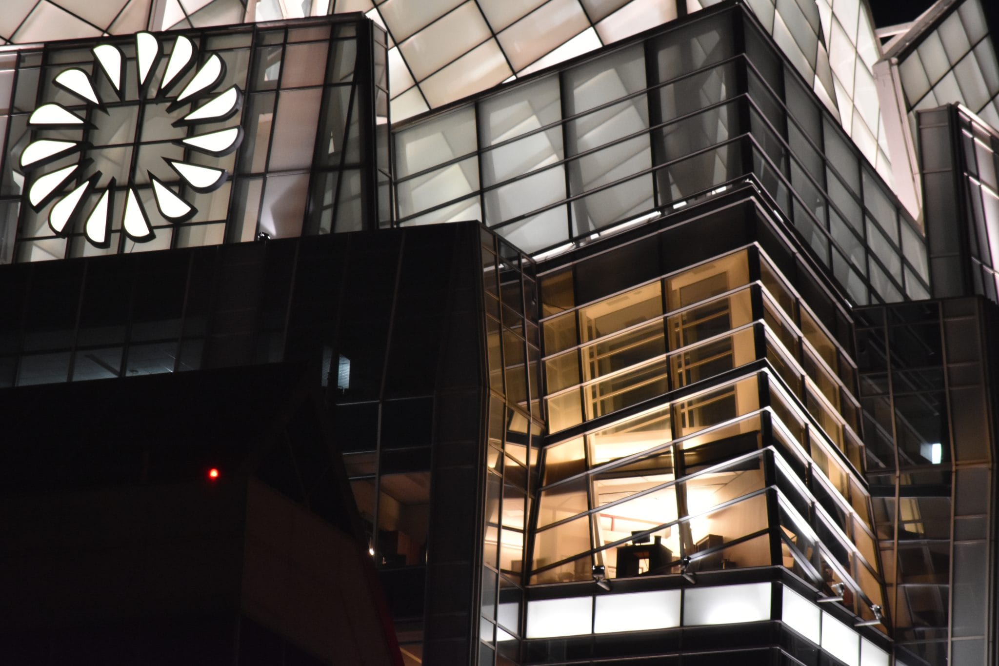 A modern glass office building lit up from within at night.