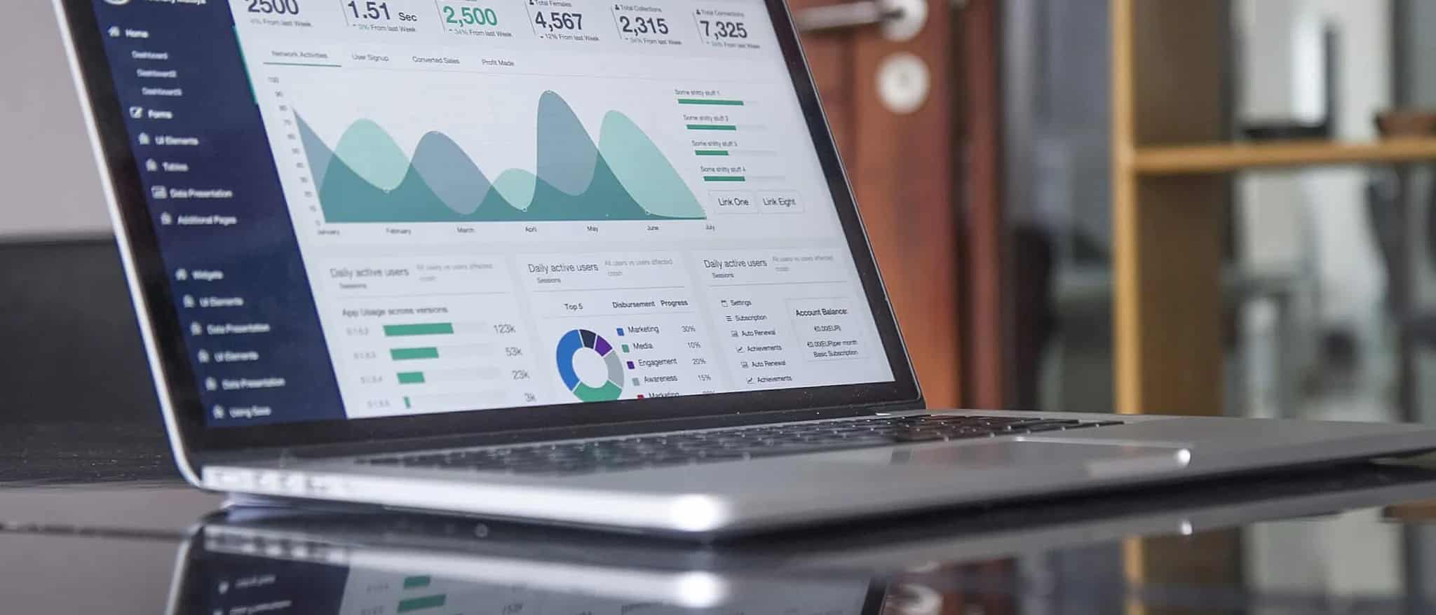 A laptop screen displaying colorful charts and statistics on a desk.