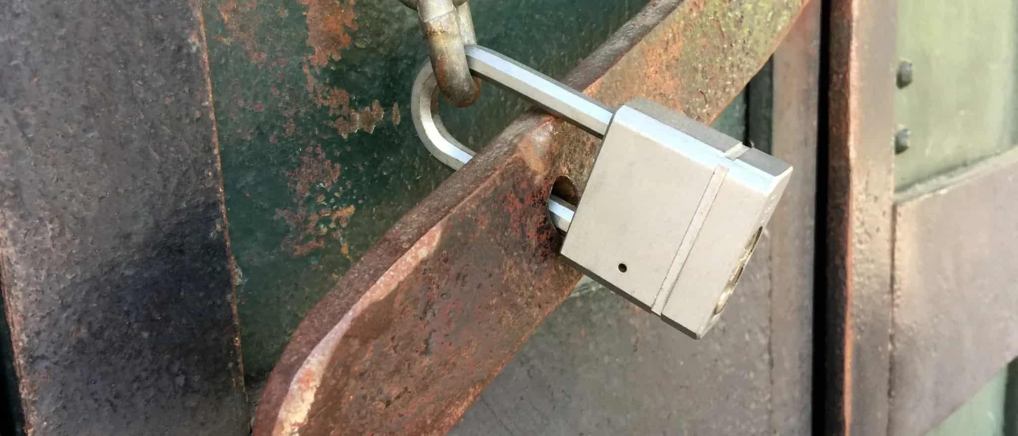 A rusty padlock securing a chain on an old, weathered metal door.