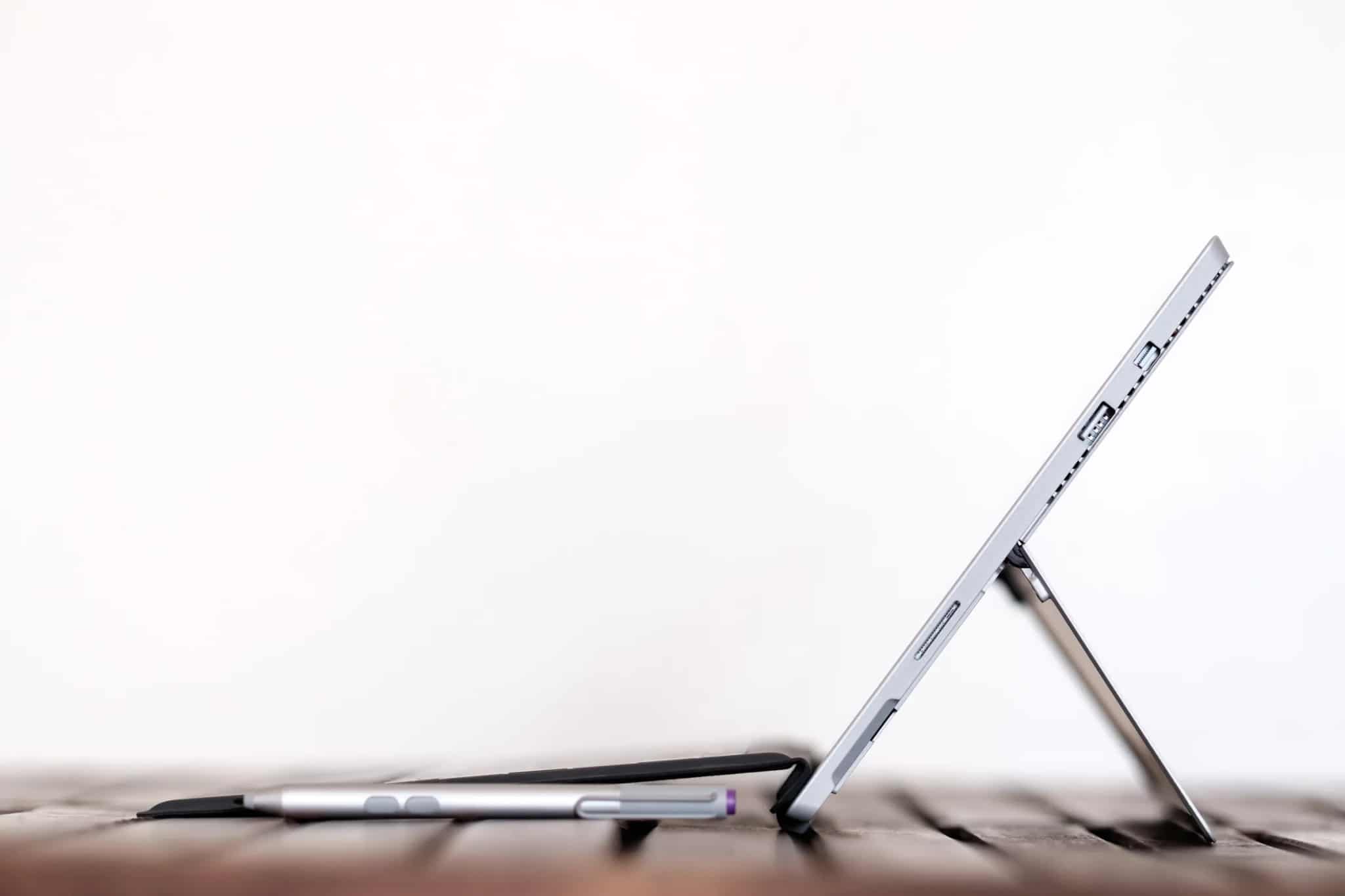 Side profile of a tablet computer propped up on its kickstand next to a stylus pen.