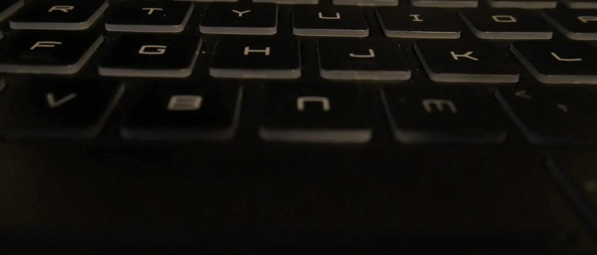 A close-up of a black laptop keyboard with worn, dusty keys.