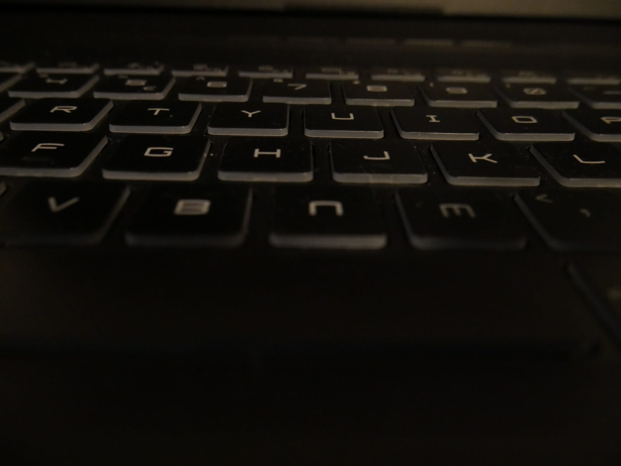 A close-up of a black laptop keyboard with worn, dusty keys.
