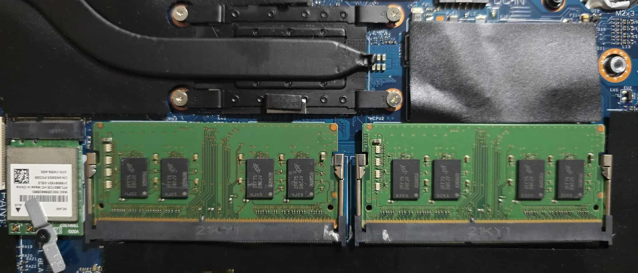 Two green RAM memory modules installed inside an open laptop's motherboard.