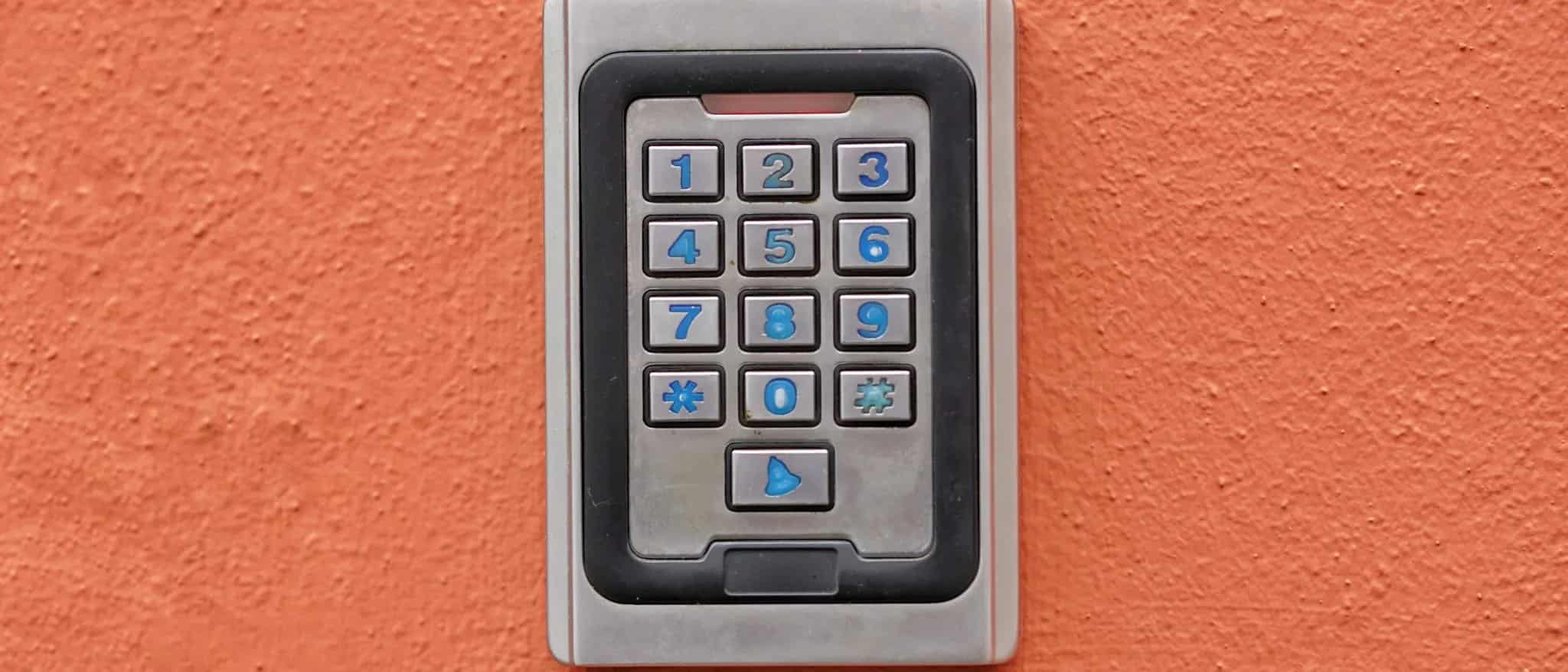 A numeric keypad access control device mounted on an orange wall.