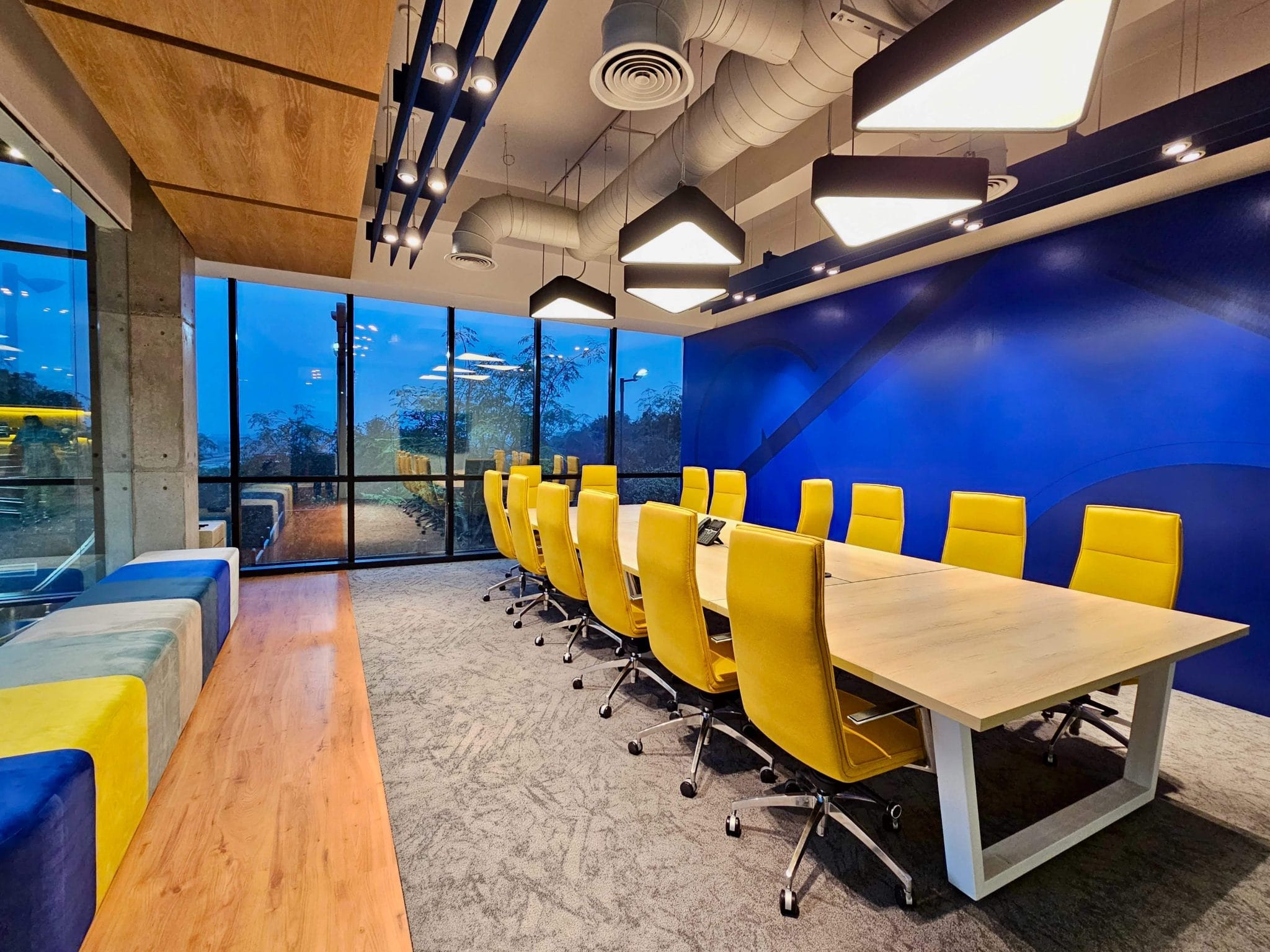 An empty modern conference room with a long wooden table and vibrant yellow chairs.