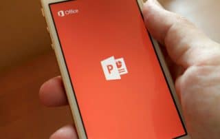 phone in palm of hand showing powerpoint logo on screen