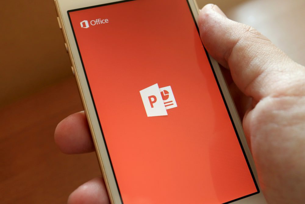 phone in palm of hand showing powerpoint logo on screen